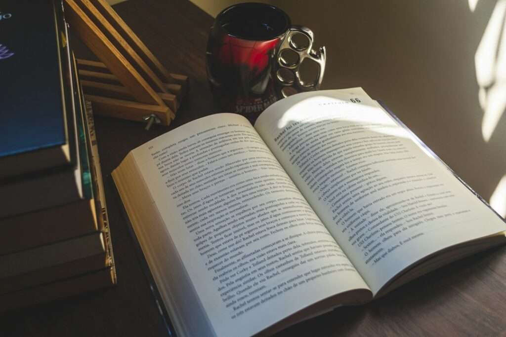 開いた本とコーヒーカップ。FANZAブックスの話読みと単行本の購入ガイド